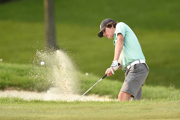 student-athlete in the st. edward high school golf program hitting the ball out of the bunker