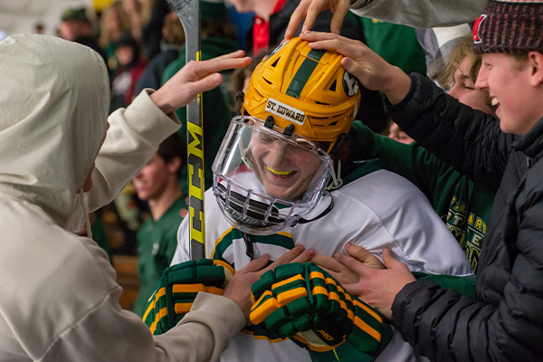 student-athletes on the st. edward high school varsity gold hockey team congratulate a teammate