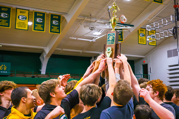 the st. edward wrestling team hoisting the divison 1 state championship trophy