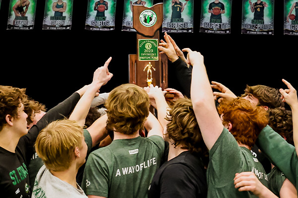 the st. edward wrestling team hoisting the 2023 divison 1 state championship trophy