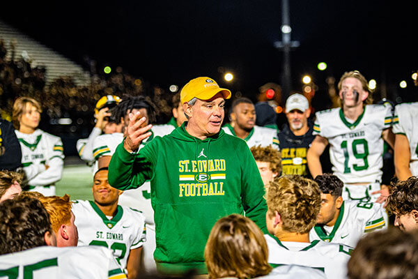 coach tom lomardo talking to the varsity football team during a timeout
