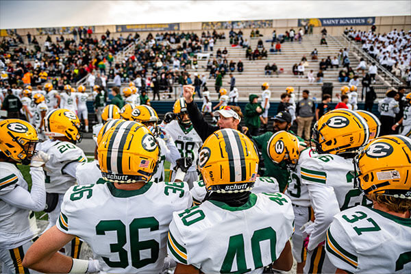 coach pete pappas in a huddle with the st. edward varsity football team