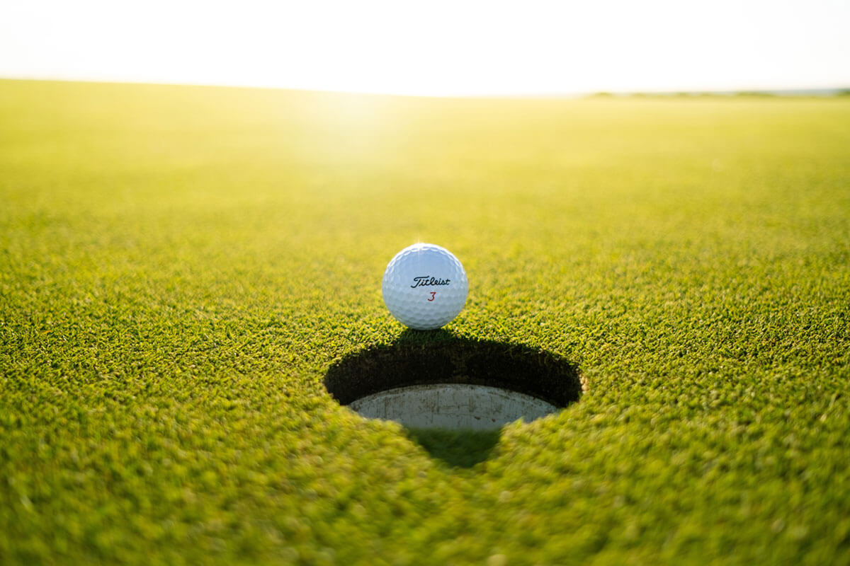 golf ball by a hole on the green