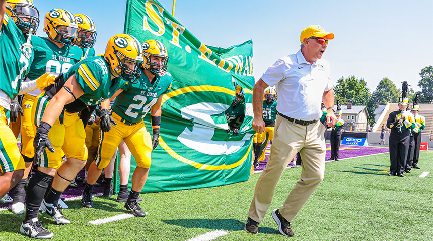 tom lombardo and the varsity football running onto the field during the espn game