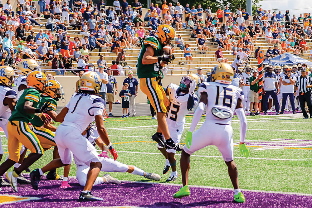 a varsity football team player jumps after scoring a touchdown