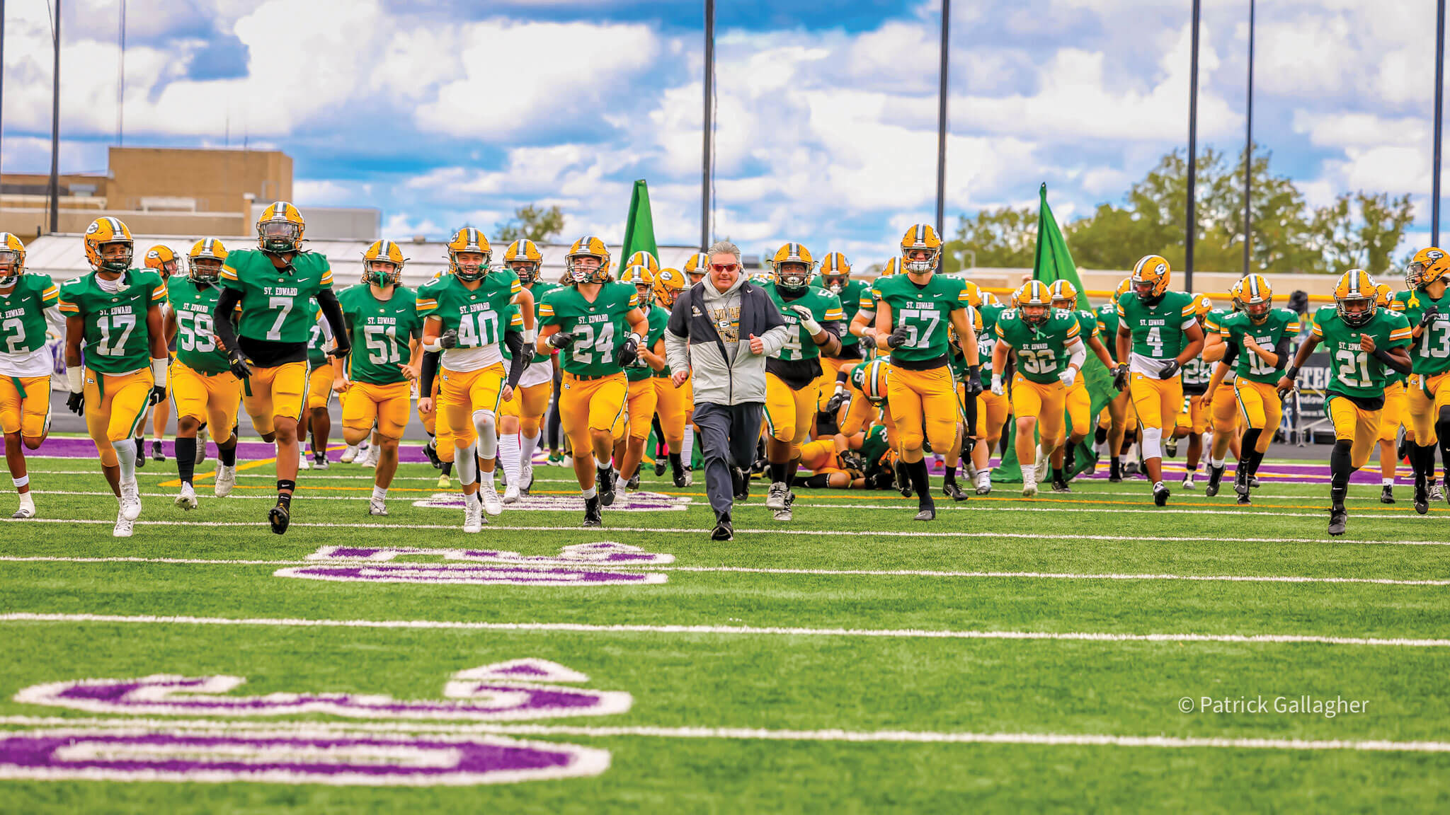 the varsity football team takes the field with head coach tom lombardo